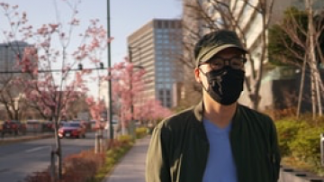 Man standing on city sidewalk wearing a mouth and nose covering mask