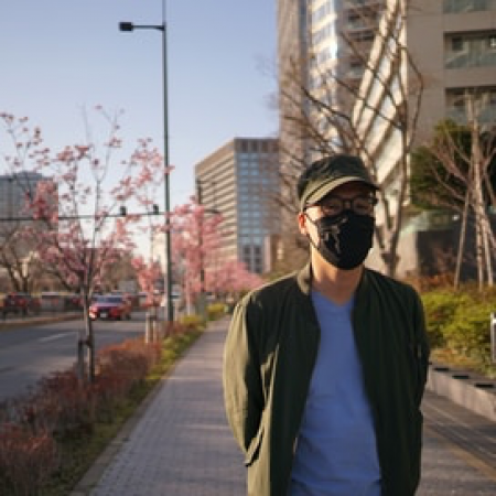 Man standing on city sidewalk wearing a mouth and nose covering mask